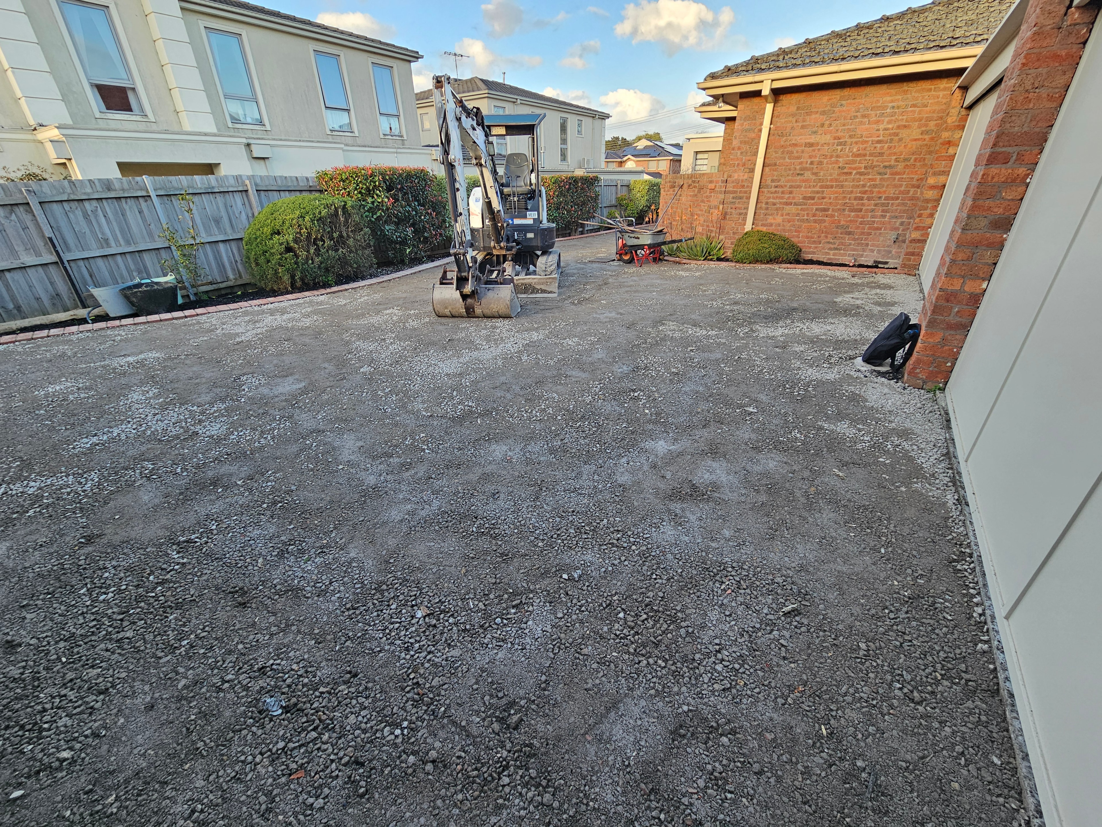 Residential driveway excavation with Bobcat and gravel base preparation