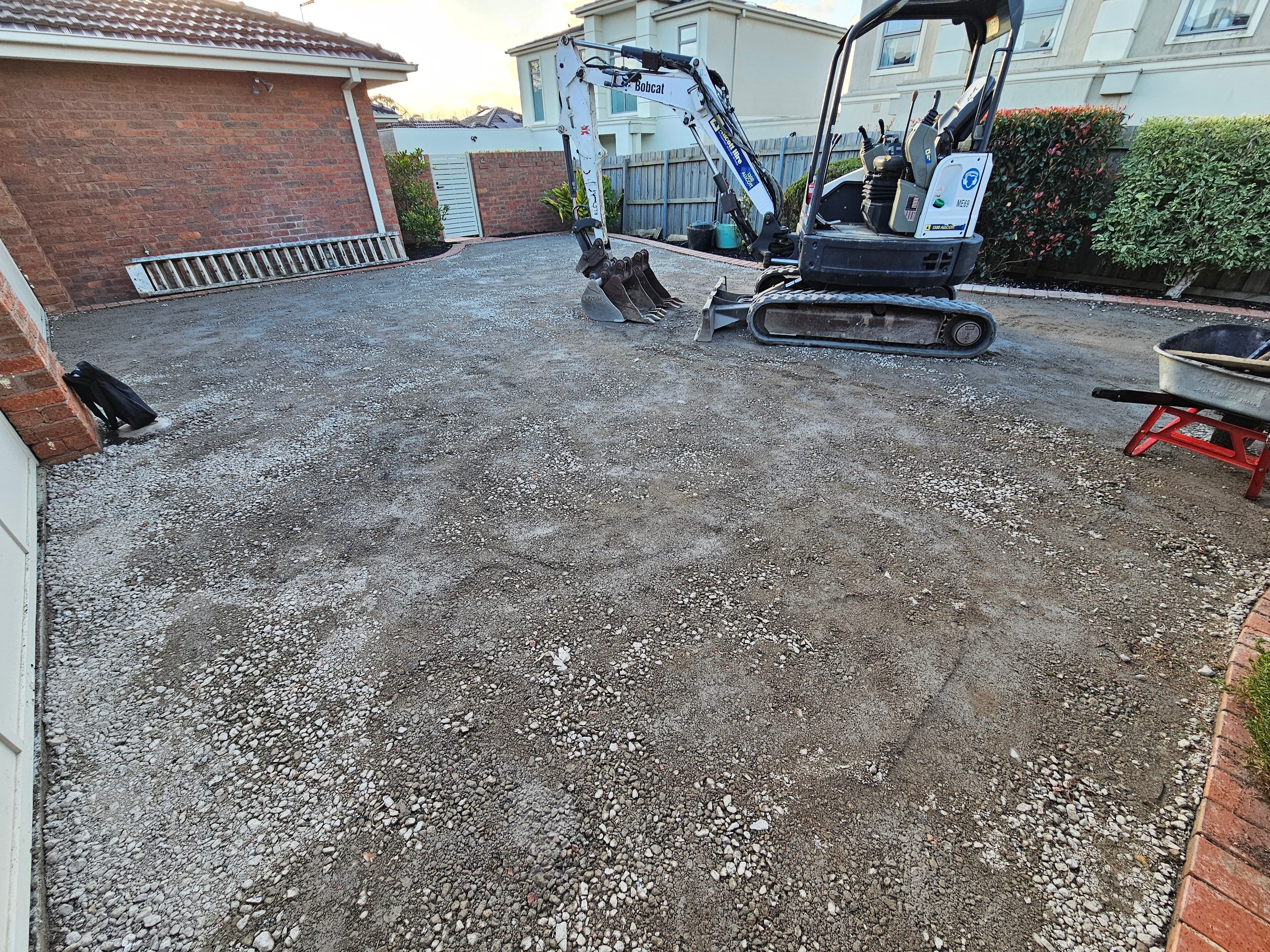 Wide angle residential driveway excavation with Bobcat and brick edging